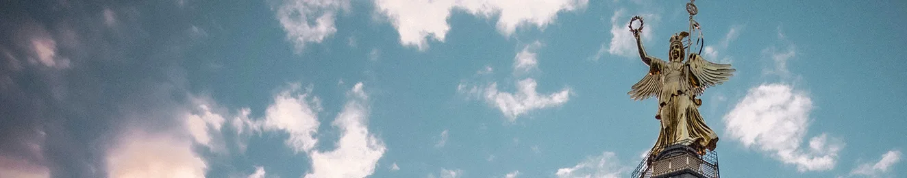siegessaele-image-wide Bild der Goldelse (der Statue auf der Berliner Sigessäule) vor blauem Himmel mit wenigen weißen Wolken.