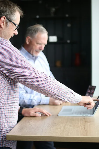  Zwei IT-Experten prüfen gemeinsam die technische Infrastruktur am Laptop – kontinuierliche Qualitätssicherung für IT Security Services.