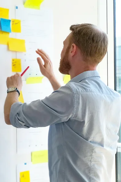 Mitarbeiter analysiert IT-Prozesse an Whiteboard mit Post-its – Startpunkt einer strukturierten IT-Beratung für Unternehmen.