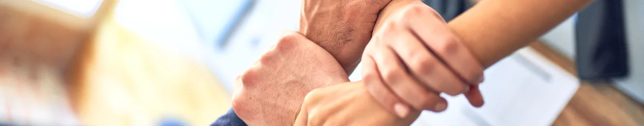 Teamwork im IT-Consulting: Vier Hände greifen ineinander und symbolisieren Vertrauen, Zusammenarbeit und die gemeinsamen Ziele eines IT-Systemhauses und dessen Kunden.
