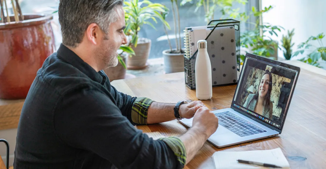 it-service_cyber-security Mann im Homeoffice spricht per Videokonferenz mit Kollegin. Dies symbolisiert sichere, standortübergreifende Zusammenarbeit im Rahmen von IT-Sicherheits- und Datenschutzmaßnahmen.