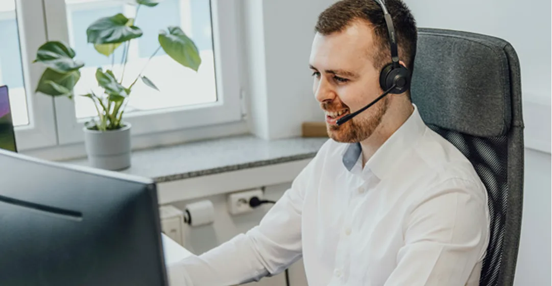 IT-Mitarbeiter mit Headset am Schreibtisch bietet telefonischen Support – persönliche Betreuung und direkte Hilfe beim IT-Service.